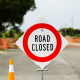 a road closed sign sitting on the side of a road
