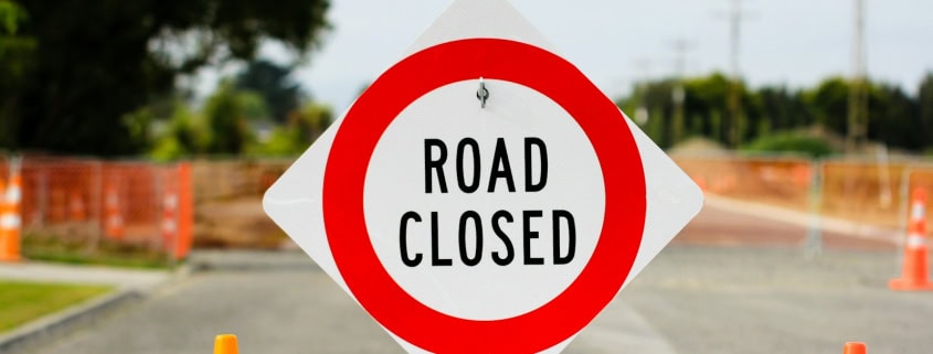 a road closed sign sitting on the side of a road