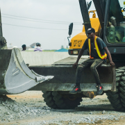 man in yellow and black jacket standing beside black and yellow heavy equipment